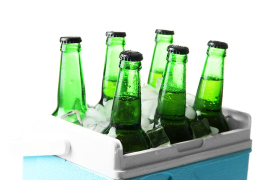 Bottles of beer with ice cubes in mini refrigerator, isolated