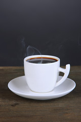 Cup of coffee on wooden table on black background