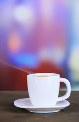 Cup of coffee on wooden table on bright background