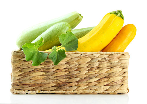 Raw yellow and green zucchini in wicker crate, isolated on