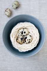 Three quail eggs in the nest with the thread on the gray plate