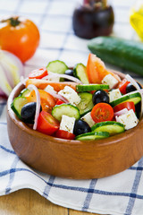 Greek salad in a wood bowl by fresh ingredients