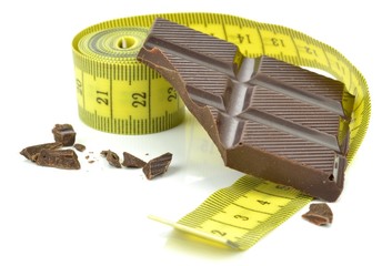 A piece of chocolate leaning on a measuring tape