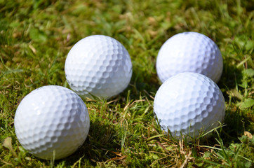 Four white golf balls in the ruff