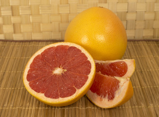 Grapefruit. Whole fruit and slices are on the table