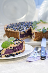 Slice of blueberry pie with mint served with knife and spoon