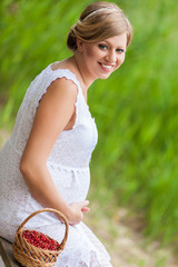 Happy pregnant woman in the green park on lake