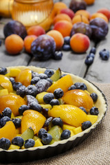 Tart with peach, pumpkin, plum and blueberry in autumn setting