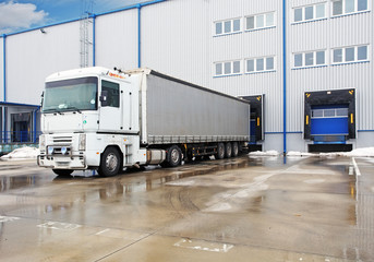 Unloading big container trucks at warehouse building - obrazy, fototapety, plakaty