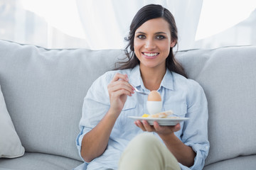 Cheerful brunette eating eggs
