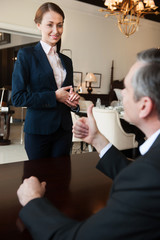 Man and sales clerk. Confident mature man in formalwear gesturin