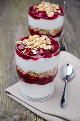 glasses with layered dessert with yogurt, granola and cherry
