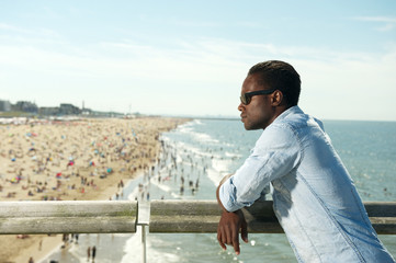 Fototapeta na wymiar Handsome black man with sunglasses relaxing at the beach
