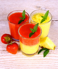 Strawberry and pineapple smoothie in glass with fruits, mint