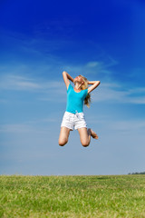 Fototapeta na wymiar happy woman jumps in a summer green field against the blue sky..