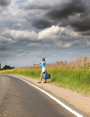 Fototapeta premium Hitchhiking girl votes on road