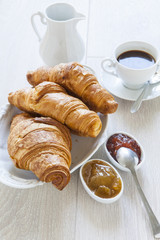 Croissants on table with jam and coffee