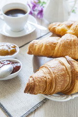 Croissants on table with jam and coffee