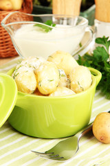 Tender young potatoes with sour cream and herbs in pan