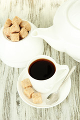 Cup of coffee, teapot and sugar-bowl on color wooden background