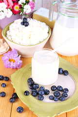 Fresh dairy products with blueberry on wooden table close-up