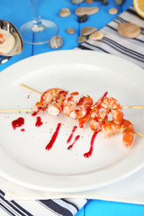 Grilled shrimp with sauce on plate on wooden table close-up