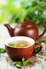 Teapot and cup of herbal tea with fresh mint flowers