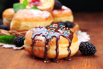 Tasty donuts with chocolate and berries on wooden table