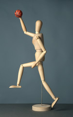 Wooden mannequin with basketball ball on grey background