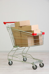 Shopping cart with carton, on gray background