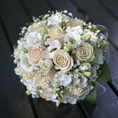 Wedding bouquet of yellow and cream roses lying on wooden floor