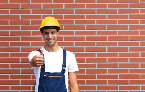 Pointing young worker in front of a brick wall
