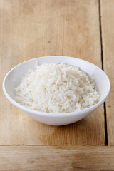White rice in a bowl on a rustic wooden background