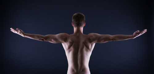 athlete stands with his back against a black background
