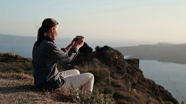 Woman taking photo of beautiful landscape with cellphone