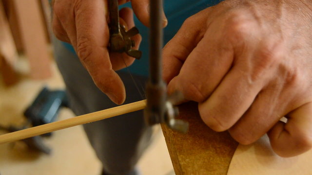 Luthier cutting a guitar piece with hacksaw