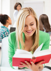 smiling student girl reading book at school