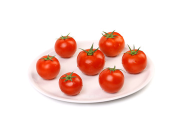 Fresh ripe cherry tomatoes on a white plant.