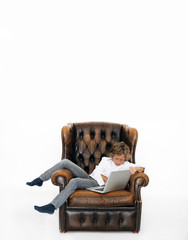 Junge relaxt im Sessel mit Laptop
