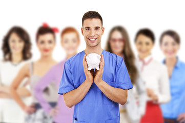 Young doctor holding piggy bank