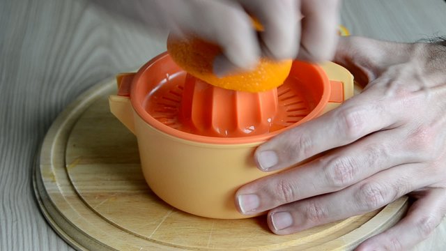 Una persona exprimiendo una naranja