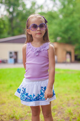 Wonderful little girl in sunglasses walking in summer park