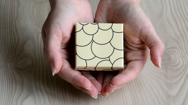 Una chica mostrando una caja de  regalo en sus manos