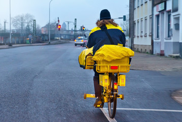 Postbotin auf Fahrrad am Morgen im Winter