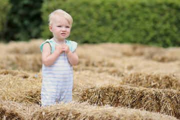 Cute baby girl stands in a middle of hay labyrinth © cromary