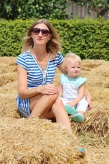Naklejka na ściany i meble Mother and daughter sitting together in hay maze