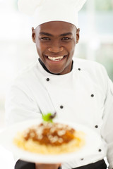 African chef in hotel kitchen presenting pasta