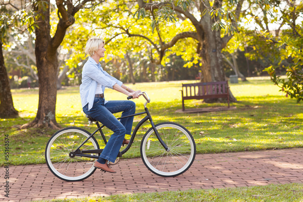 Wall mural mature woman riding a bike at the park