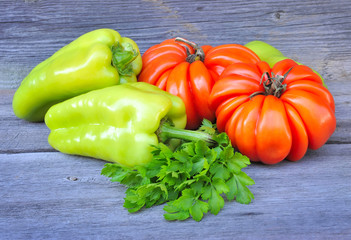 Fresh tomatoes, sweet green peppers and parsley on an old wooden