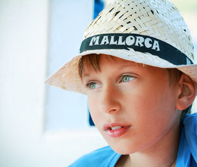 cute smiling blond boy wearing a straw hat on vacation